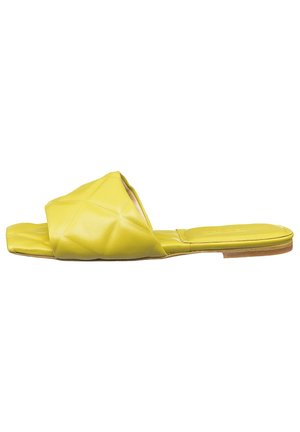 Yellow leather slide sandal with a quilted upper, flat sole, and open toe design. Simple, minimalist style with a smooth texture.