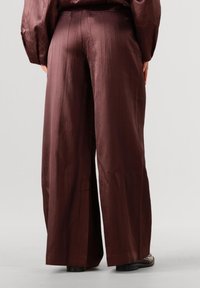 Wijde broek in een diep bordeauxrode kleur, met een gestructureerde, gladde stof. Zichtbare verticale plooien en een getailleerde tailleband.