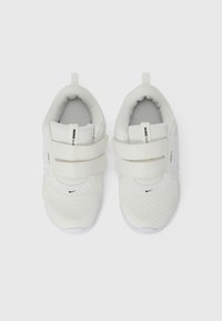 White athletic shoes with mesh fabric, two Velcro straps, padded collar, and Nike logo accents. Lightweight and flexible design.