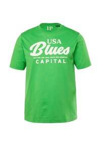 Zelené bavlněné tričko s krátkým rukávem, které má bíle tištěný nápis "USA Blues" a další fráze, kulatý výstřih a volný střih.