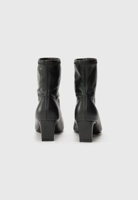 Sorte lær ankle boots med blokkhæl, som har et slankt design, tekstureret overflade og subtile syninger langs sømmene.
