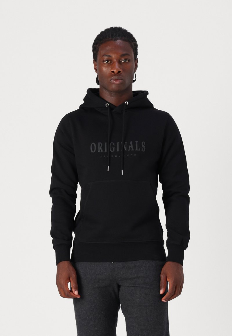 Sudadera negra con capucha y bolsillo frontal. Logo "Originals" impreso en un acabado mate oscuro. Textura de tela simple y suave.
