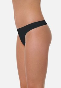 String noir en matériau lisse, avec un design minimaliste, des côtés étroits et une taille élastique. Aucun motif ni accent présent.