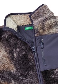 Fleece bunda s tmavě a světle hnědým abstraktním vzorem, vysokým límcem, kapsou na zip a měkkou texturou. Viditelná zelená nášivka.