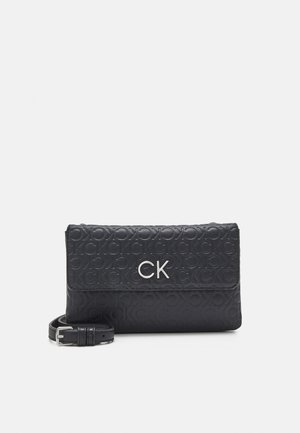 Czarna torebka Calvin Klein na ramię z wypukłym wzorem logo CK, srebrnymi literami CK na przedniej klapie i regulowanym paskiem z klamrą.
