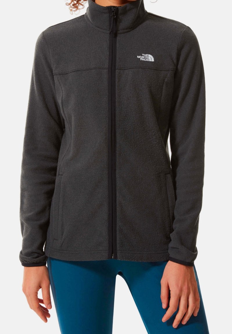 Mörkgrå fleecejacka med hög krage, hel dragkedja och två sidofickor. Har ett subtilt strukturerat mönster och svarta detaljer.