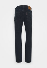 Jean bleu foncé à jambes droites vu de dos avec deux poches arrière, passants de ceinture et un patch en cuir marron à la taille.