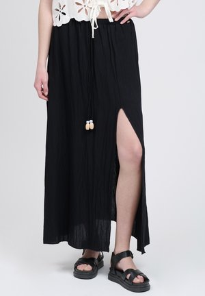 Sort maxinederdel af letvægtsstof med siderib, elastisk talje og dekorative kvaster. Enkel, flydende design.