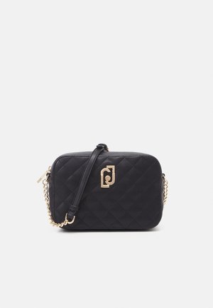 Schwarze gesteppte Leder-Umhängetasche mit goldener Kettenriemen und goldenem Markenverschluss auf der Vorderseite vor weißem Hintergrund.