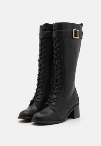 Black leather knee-high boots with a lace-up front, side zipper, and block heel. Features a buckle accent near the top.