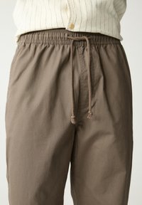 Bordeaux elastische tailleband broek met een koord, met een gladde textuur en een ontspannen pasvorm. Geen zichtbare patronen of accenten waargenomen.