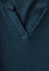 Kurzärmliges Poloshirt in dunkelblaugrün mit V-Ausschnitt und feiner Struktur. Verfügt über gestickte Nähte und einen lockeren Schnitt.