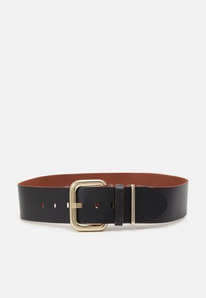 Ceinture large en cuir texturé noir avec une grande boucle carrée dorée et plusieurs trous de réglage sur fond blanc.