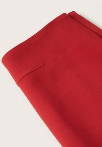 Tissu rouge texturé plié soigneusement, affichant une surface lisse et un bord net. Aucun motif ou élément matériel visible.