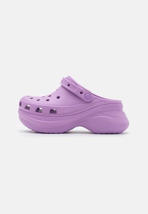 Sabot violet clair à enfiler avec trous de ventilation, bride réglable et semelle plateforme épaisse sur un fond clair uni.
