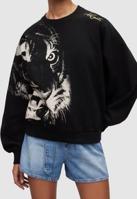 Černá mikina s velkým bílým tygrem na přední straně, s žebrovanými manžetami, volným střihem a jemným zlatým logem na rameni.
