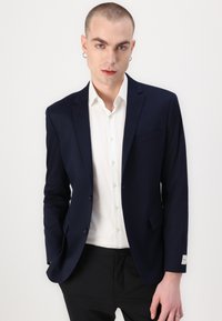 Navy blazer gecombineerd met een wit overhemd, heeft een getailleerde fit, notch-revers en een enkele borstzak voor een verzorgde uitstraling.