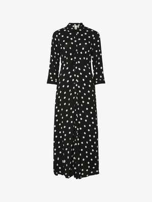 Vestido preto de botões com mangas três quartos. Apresenta grandes bolinhas brancas, um colarinho e um detalhe de cintura ajustada. O tecido fluido cai elegantemente.