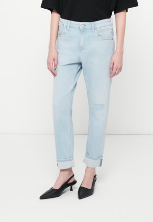 Ανοιχτό μπλε τζιν παντελόνι με άνετη εφαρμογή, καμποτάδες μανικιών, μπροστινές τσέπες και φθαρμένες λεπτομέρειες. Συνδυασμένο με μαύρες γόβες slingback.