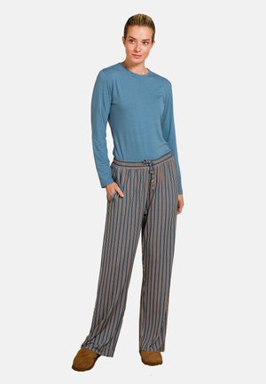 Blauw langemouwen shirt gecombineerd met gestreepte wijde pantalons met oranje en marineblauwe lijnen. Tan slippers maken de outfit af.