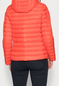 Rød dunjakke med hætte, der har et quiltet design, glat finish og en tæt pasform. Synlige syninger og en kort længde fuldender looket.