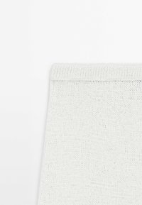 Tessuto bianco lavorato a maglia con una texture liscia, caratterizzato da un semplice bordo ripiegato nella parte superiore, adatto per varie applicazioni.