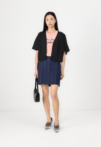 Svart kortärmad kimono-jacka, rosa T-shirt med blommönster, blå denimkjol med vertikala ränder, silverfärgade skor och en rund svart väska.