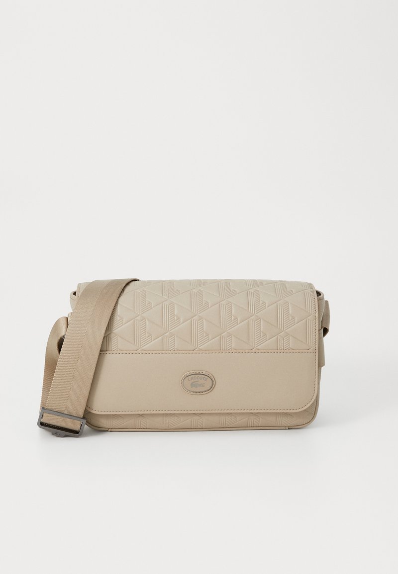 Borsa a tracolla beige realizzata in materiale sintetico testurizzato, caratterizzata da un motivo geometrico, tracolla regolabile e un logo rotondo di accento.