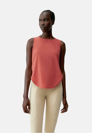Top rojo sin mangas hecho de una tela suave, con un dobladillo redondeado y un sutil logo en el centro, combinado con leggings beige ajustados.