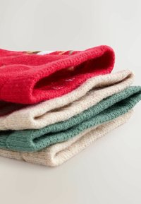 Vier opgevouwen gebreide sokken in rood, beige en groen. Elke sok heeft een zachte textuur, met de rode sok die een patroon nabij de boord heeft.