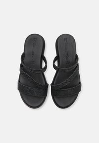 Sandales noires avec des bretelles croisées ornées de clous décoratifs, semelle plate et un design simple à enfiler. Taille 37 embossée sur la semelle intérieure.