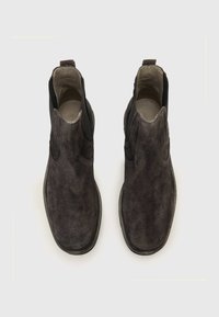 Stivaletti alla caviglia in suede grigio scuro con pannelli laterali elasticizzati, punta arrotondata e suola in gomma bassa. Fodera interna liscia e design minimale.