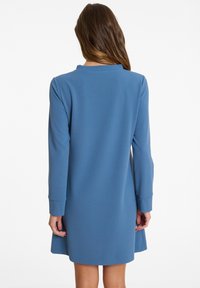 Langärmliges Kleid aus weichem blauen Stoff, mit rundem Ausschnitt, lockerer Passform und ausgestelltem Saum, mit gerippten Bündchen und Rückendetail.