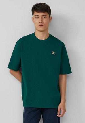 Grünes Baumwoll-T-Shirt mit Rundhalsausschnitt, kurzen Ärmeln und einem kleinen gestickten Design in der Nähe der Brust. Einfaches und lässiges Design.