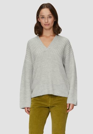 Lichtgrijze gebreide trui met een v-hals, ruime mouwen en een gestructureerde stof, gecombineerd met olijfgroene corduroy broek.