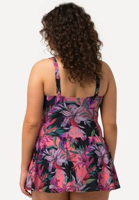 Robe de bain avec un fond noir et des motifs floraux colorés en rose, violet et vert. Comprend des bretelles réglables et une jupe évasée.