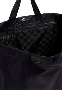 Bolso negro con una superficie texturizada, que cuenta con un cierre superior de presión, dos asas resistentes y un forro a cuadros con un bolsillo interior con cremallera.