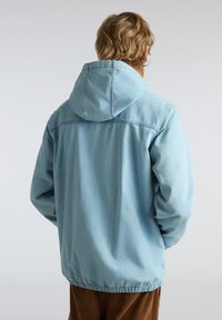 Lichtblauwe hoodie-jack met een relaxte pasvorm, elastische zoom en een zachte denimstructuur. Heeft een eenvoudig ontwerp en zichtbare stikdetails.