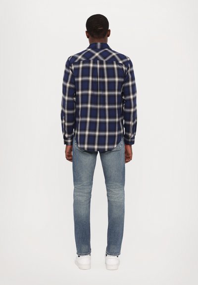 Ruuduline sinine ja valge flanellpusa, nupuga krae, selja voldi detail, koos helesiniste teksade ja valgete tossudega.