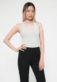 Gray, sleeveless bodysuit with a deep V-neck paired with black fitted trousers, showcasing a smooth texture and casual design.