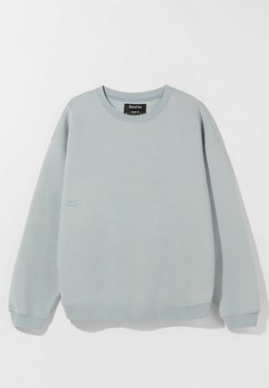Lichtblauwe sweatshirt van zachte stof, met een ronde hals en geribbelde manchetten. Een klein bedrukt detail aan de voorkant voegt interesse toe.