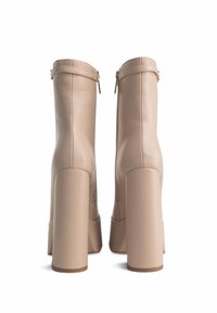 Stivali platform in finta pelle beige con tacco alto a blocco, dotati di chiusura con zip sul retro e una finitura liscia e testurizzata.