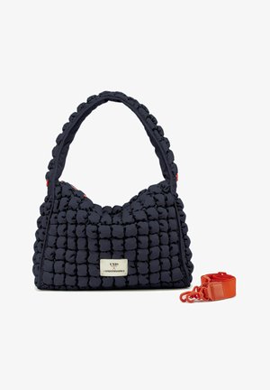 Sac en bandoulière matelassé bleu marine avec une texture duveteuse, doté d'une poignée courte et d'une bandoulière orange amovible. Présente une étiquette logo en argent.