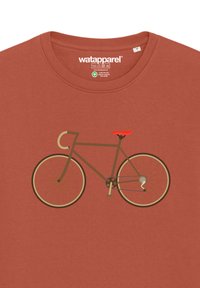 Bruine T-shirt met een eenvoudig, grafisch ontwerp van een fiets met een rode zitting, crèmekleurige wielen en een contrasterende achtergrond. Zachte stoffen textuur.