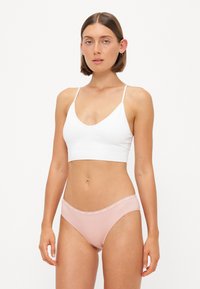 White ribbed bralette with thin straps paired with light pink bikini bottoms featuring a soft waistband. Smooth texture, simple design.