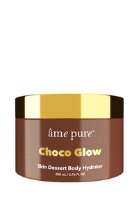Brun burk med ett guldlock. Etiketten visar "Choco Glow Skin Dessert Body Hydrator, 200 mL." Slät textur, modern design, minimala grafik.