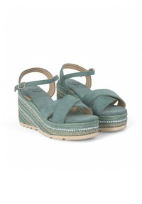 Groene suède wedge sandalen met kruislings banden, gevlochten jute platform en decoratieve kraalaccenten langs de zool.
