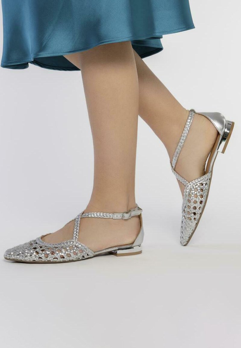 Scarpe piatte argento con design a trama aperta, punta affusolata e cinturino alla caviglia. Presentano una finitura metallica e un tacco piccolo.