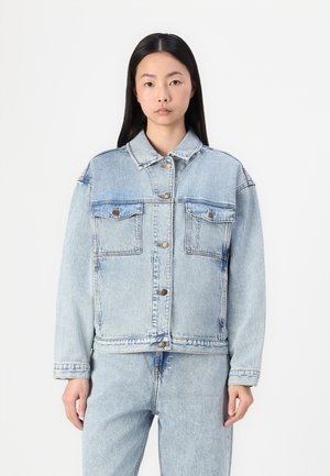 Chaqueta de mezclilla azul claro con botones en el frente, dos bolsillos de parche y un corte relajado. Textura suave con un diseño informal y costuras visibles.
