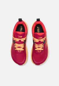 Baskets de trail de course rouges et orange avec un dessus en maille, des lacets contrastants et une semelle en caoutchouc texturé. Présente une languette à l'arrière.
